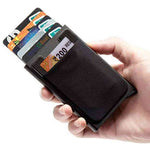 Hand holding a black cardholder with multiple cards, including a bank card, on a white background.